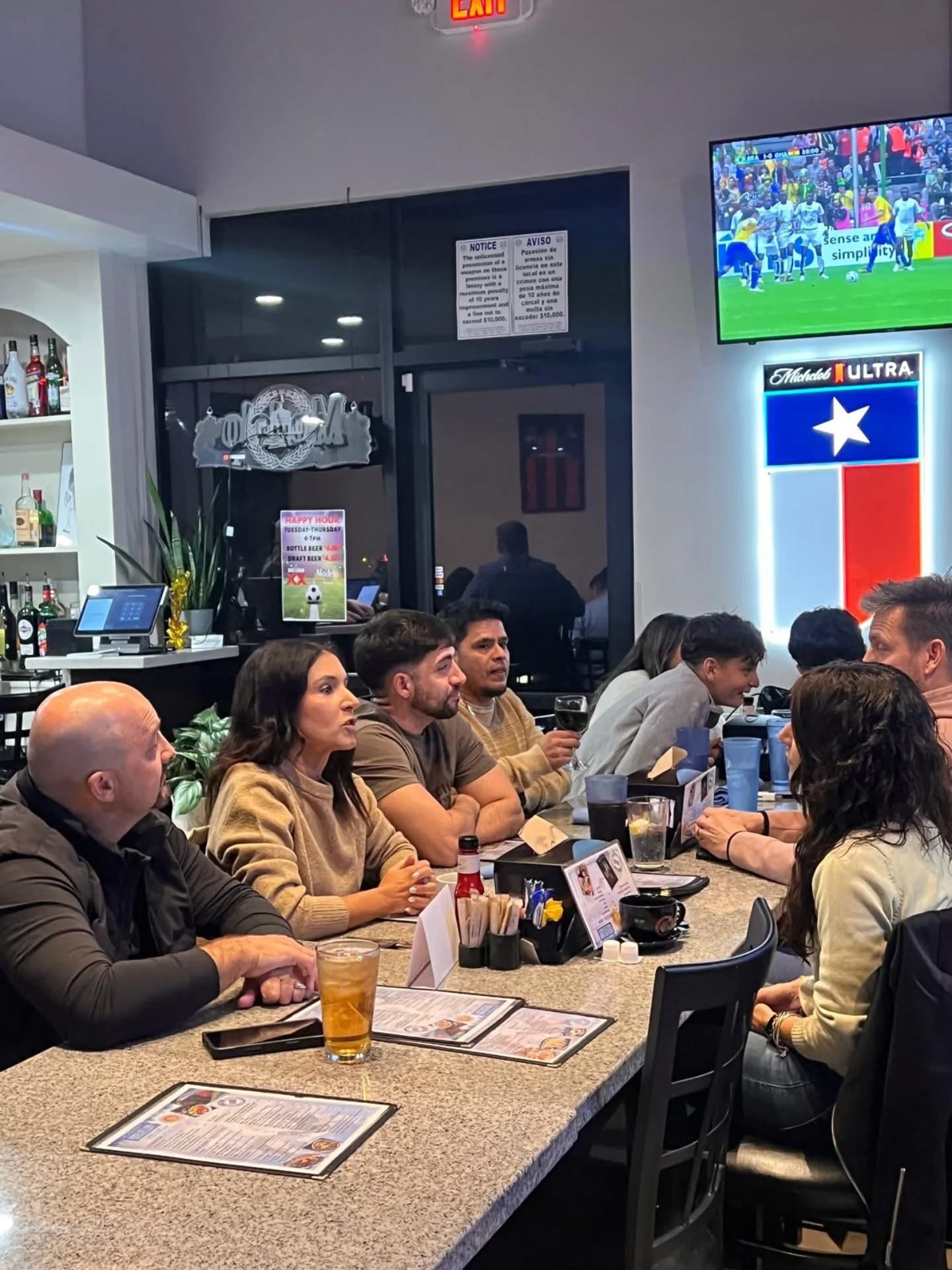 Amigos en la barra con la bandera de Texas y fútbol en pantalla